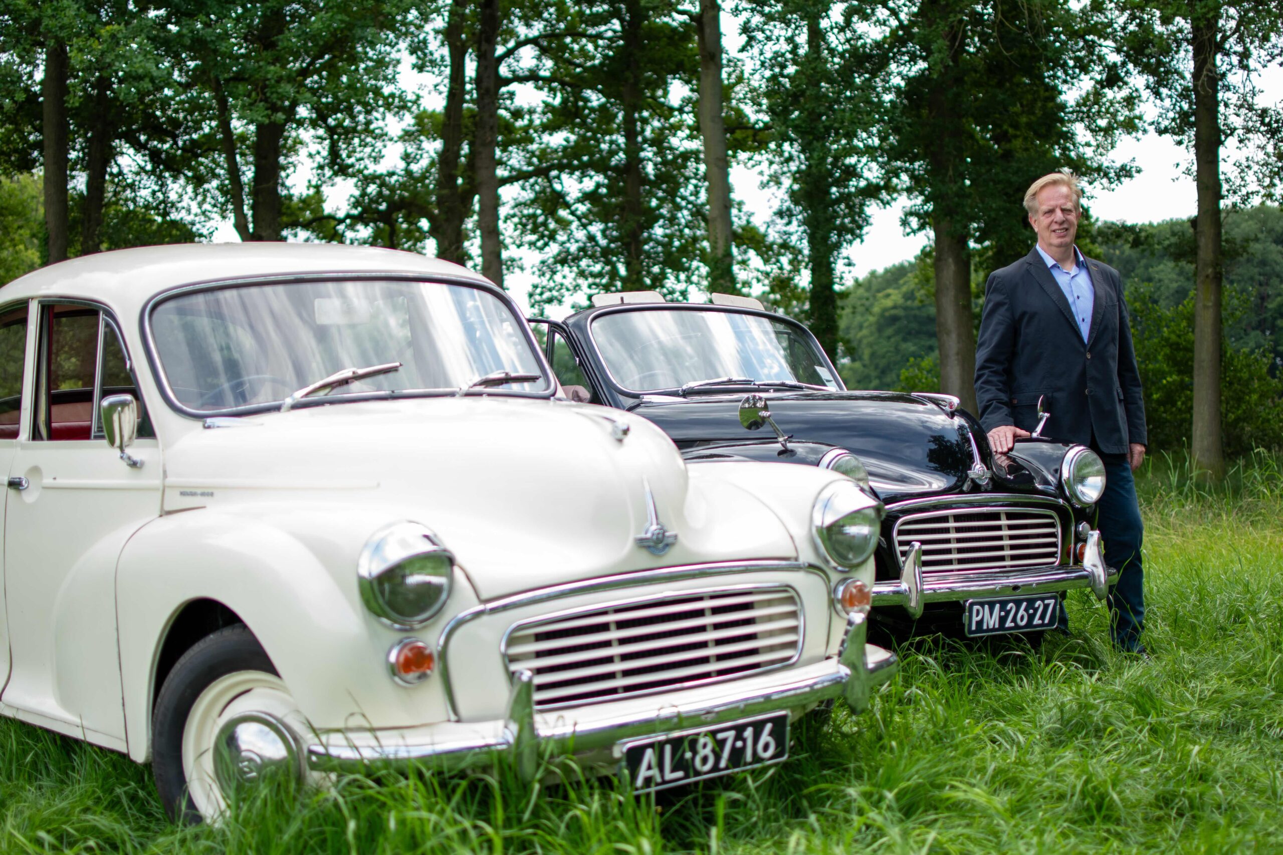 Eigenaar met beide Morris Minor trouwauto's in de wei